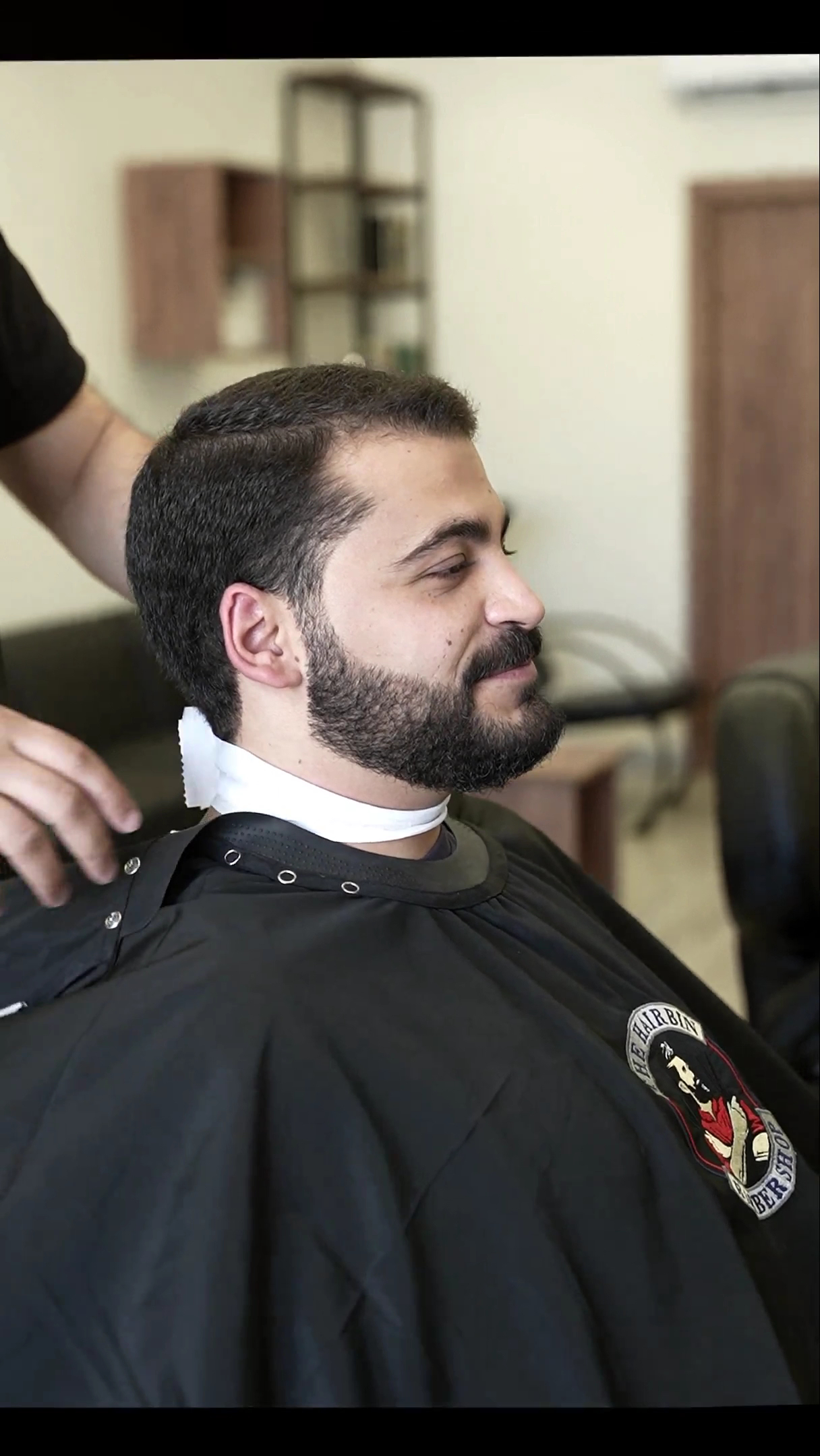 Client with a freshly groomed beard, branded Hairbin cape visible