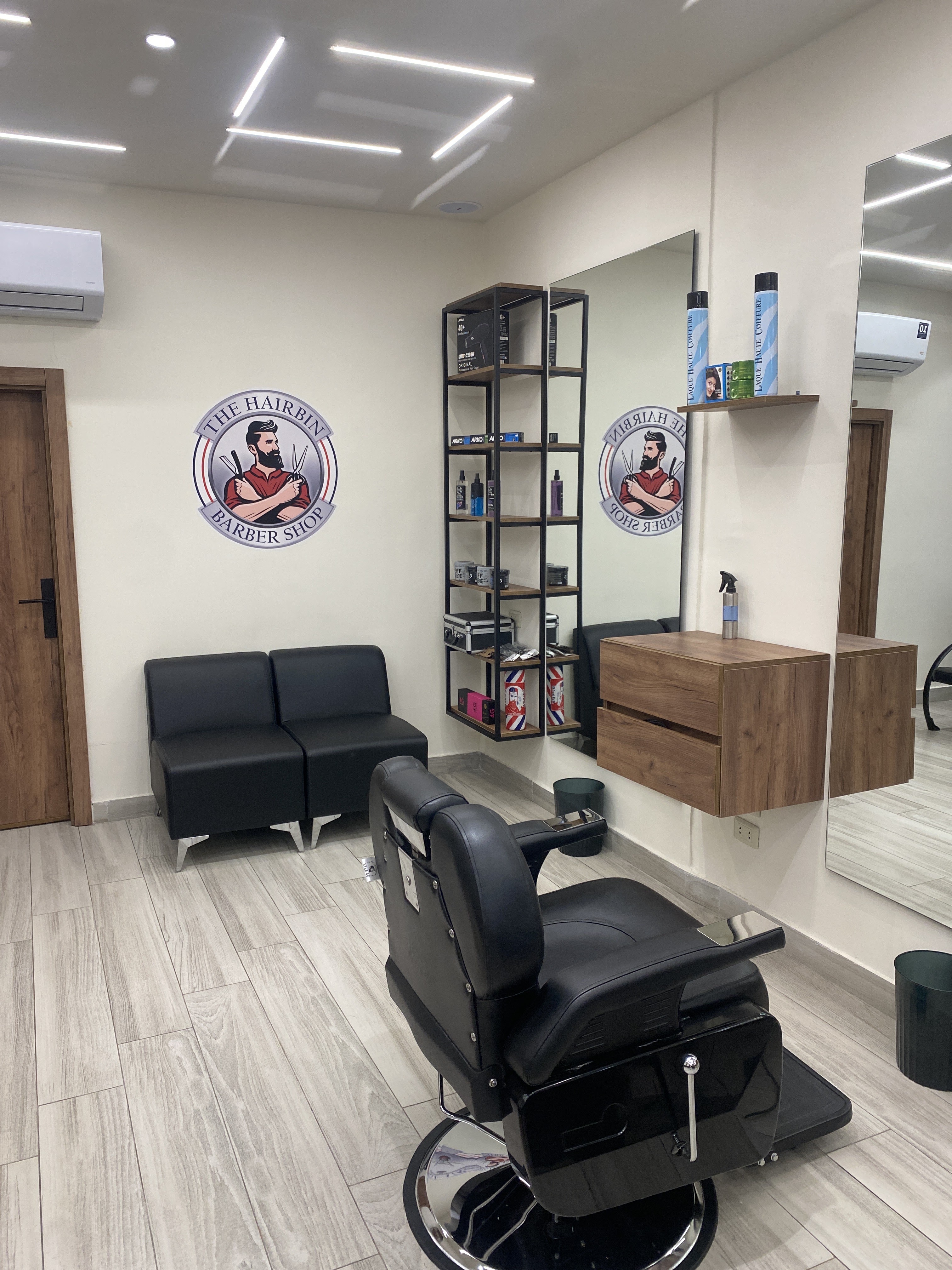 The Hairbin Barber Shop logo on the wall above the waiting area