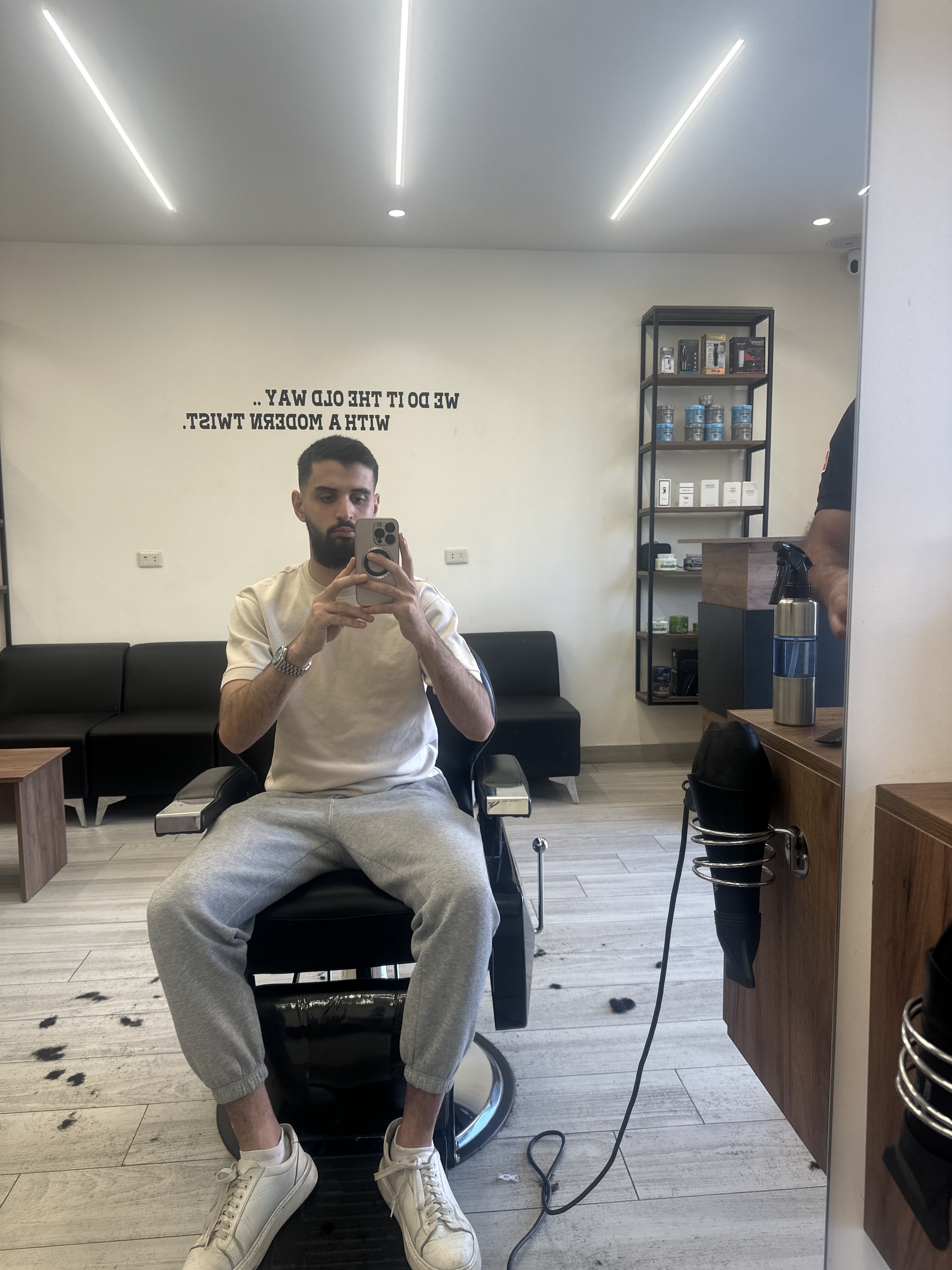 Client seated in the barber chair beneath the shop's wall lettering
