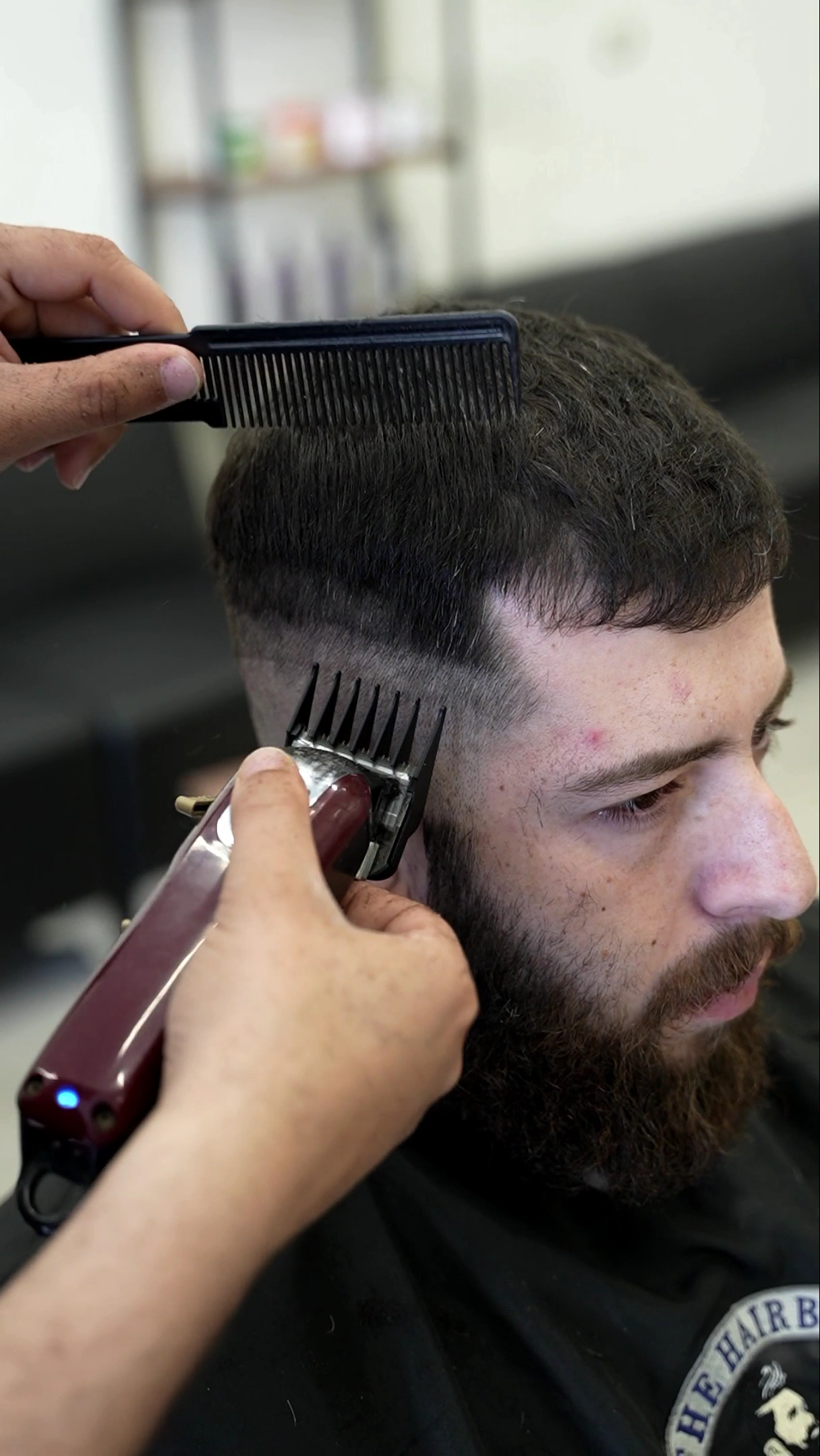 Close-up of a clipper fade in progress, comb in hand at The Hairbin