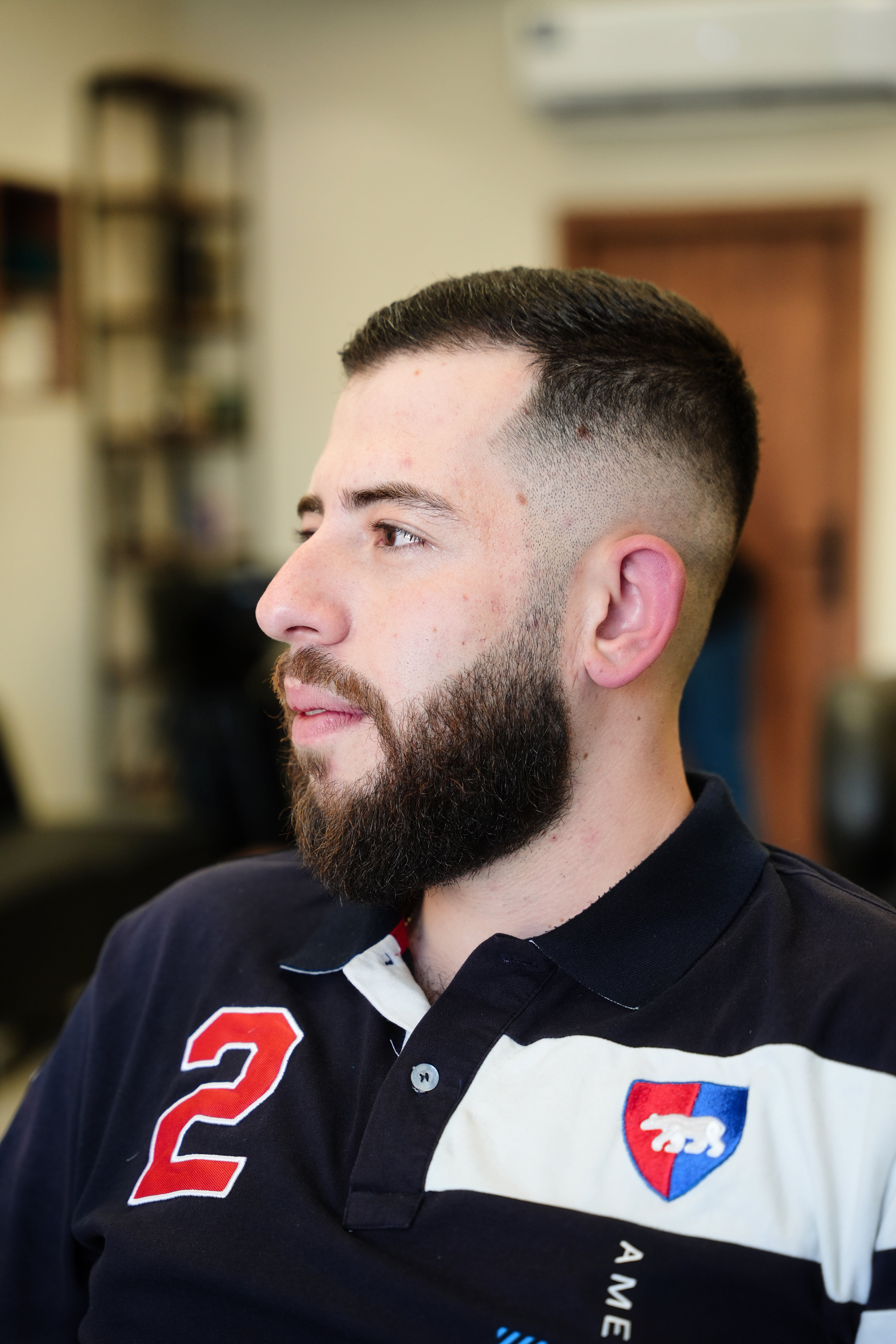 Side profile of a clean taper fade with a full groomed beard